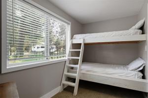 a bedroom with bunk beds and a window with a ladder at Bluebird Day - Brooks House in Deschutes River Woods