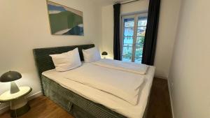 a bed with white sheets and a window in a room at Casa Tantris zentral und modern mitten in Gmund in Gmund am Tegernsee