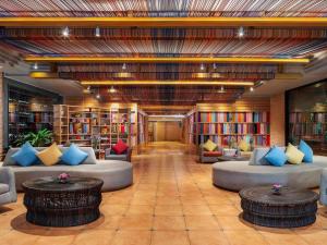 a library with couches and tables in a room with books at Mercure Bangkok Sukhumvit 11 in Bangkok