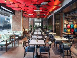 a restaurant with tables and chairs and red umbrellas at Mercure Bangkok Sukhumvit 11 in Bangkok