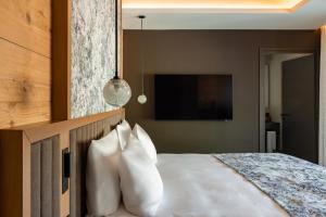 a bedroom with a bed with white pillows and a tv at HUUS QUELL by Appenzeller Huus in Gonten