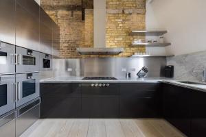 a kitchen with black cabinets and stainless steel appliances at Comfortable luxury apartments near the Center - London in Southport