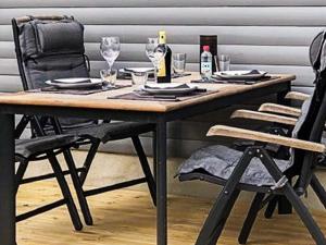 a wooden table with two chairs and a bottle of wine at 4 person holiday home in LÖDDEKÖPINGE in Löddeköpinge