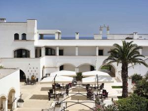 a large white building with tables and umbrellas at Borgobianco Resort & Spa Polignano - MGallery Collection in Polignano a Mare