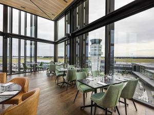 a restaurant with tables and chairs and windows at Novotel Christchurch Airport in Christchurch