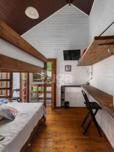 um quarto com uma cama e uma escrivaninha com uma televisão em Suíte Front Paraíso dos Ciclistas em Gramado