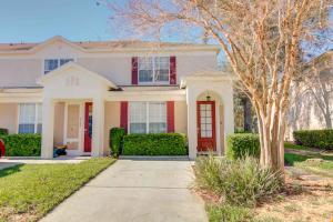 une maison blanche avec une porte rouge et un arbre dans l'établissement Veteran Owned 3bdr/3 bath Townhouse w/WiFi 3mi to Disney - Winter/Spring Specials, à Kissimmee