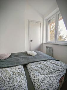 a bed in a white room with a window at Kopaonička priča in Kopaonik