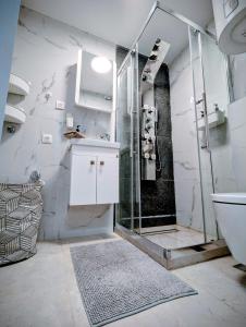 a white bathroom with a shower and a sink at Kopaonička priča in Kopaonik