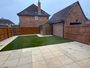 einen Hinterhof mit einem Holzzaun und einem Rasen in der Unterkunft Randall House in Wootton