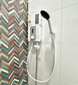 a shower with a hose attached to a wall at D sleep Home Chiangmai in Chiang Mai