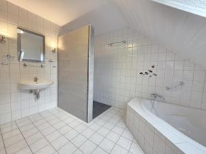 Komfortferienhaus Küstenruhe Norddeich في Flüthörn: حمام أبيض مع حوض استحمام ومغسلة +35 صورة