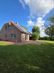Komfortferienhaus Küstenruhe Norddeich في Flüthörn: منزل من الطوب مع حديقة خضراء أمامه