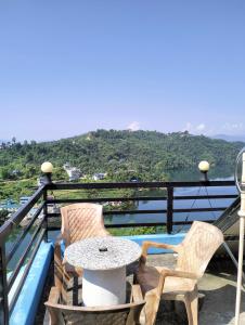 a table and chairs on a balcony with a view at Hotel bright moon lake in Deorāli
