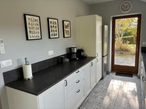 a kitchen with white cabinets and a black counter top at La Maison du Clocher in Jupilles