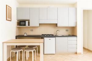 a kitchen with white cabinets and bar stools at Studio Sole e Residenza Luna Assisi in Assisi