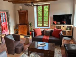 a living room with a couch and a tv at La Maison du Clocher in Jupilles