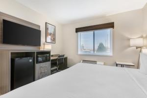a hotel room with a bed and a flat screen tv at Best Western Gold Poppy Inn in Tucson