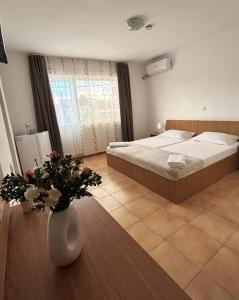 a bedroom with a bed and a vase with flowers at Casa Silvia in Costinesti +8 photos