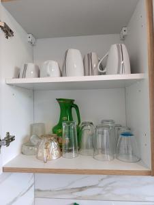 a shelf filled with dishes and a green vase at résidence KAKIKA in Verviers +4 photos