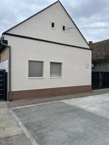a white building with three windows on the side of it at Prenociste-apartmani Laki S in Kula