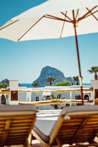 a couple of chairs and an umbrella on a beach at Petunia Ibiza, a Beaumier hotel in Cala Vadella +97 photos