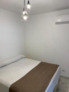a white bedroom with a bed and two lights at Atlantico Flat Santos in Santos