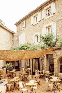 an outdoor patio with tables and chairs in front of a building at Le Moulin, Lourmarin, a Beaumier Hotel in Lourmarin +88 photos