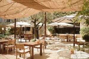 a restaurant with tables and chairs and umbrellas at Le Moulin, Lourmarin, a Beaumier Hotel in Lourmarin