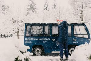 a person standing in the snow next to a truck at Grand Hotel Belvedere, a Beaumier Hotel in Wengen