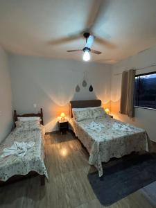 a bedroom with two beds and a ceiling fan at Tríade Chalé da Canastra 2 in São Roque de Minas +90 photos