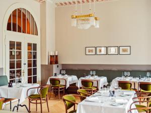 a restaurant with white tables and chairs and a chandelier at Grand Hotel Belvedere, a Beaumier Hotel in Wengen