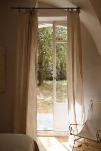 een slaapkamer met een glazen schuifdeur met een stoel bij Le Galinier Lourmarin, a Beaumier Guesthouse in Lourmarin
