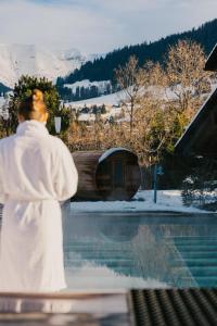 een man in een wit gewaad die naast een zwembad staat bij L'Alpaga, a Beaumier hotel in Megève