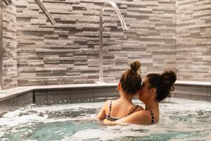 twee vrouwen zitten in een zwembad bij L'Alpaga, a Beaumier hotel in Megève