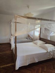 a bedroom with a canopy bed with white sheets at Oasis Kemba Hôtel-Restaurant-Bar in Toliara