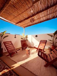 a patio with two chairs and a table and a roof at Vagusta Surf House in Agadir