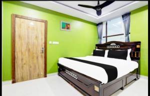 Un dormitorio con una cama con una pared verde. en Savoygrandluxuryrooms, en Warangal
