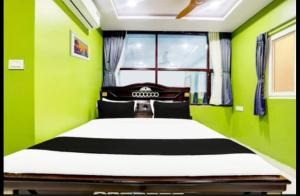 Un dormitorio con una cama con paredes verdes y una ventana en Savoygrandluxuryrooms, en Warangal