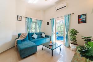 ein Wohnzimmer mit einem blauen Sofa und einem Tisch in der Unterkunft Lavish 3bhk villa by bluewave hospitalty in Nagoa-Bardez