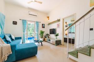 ein Wohnzimmer mit einer blauen Couch und einem Bett in der Unterkunft Lavish 3bhk villa by bluewave hospitalty in Nagoa-Bardez