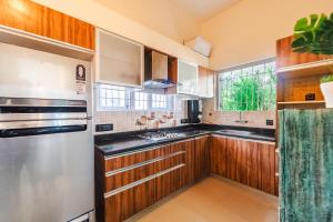 eine Küche mit Holzschränken und einem Edelstahlkühlschrank in der Unterkunft Lavish 3bhk villa by bluewave hospitalty in Nagoa-Bardez