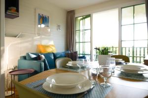 une table de salle à manger avec des assiettes et des verres dessus dans l'établissement Appartement vue golf - résidence Saint Laurent - 4 personnes, à Talmont-Saint-Hilaire