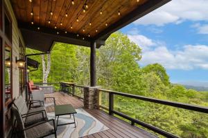 Una terraza con sillas y una mesa y una vista al bosque. en Cardinal Perch, en Beech Mountain