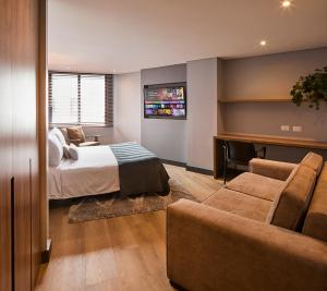 a hotel room with a bed and a couch at Nico Apartasuites in Bogotá