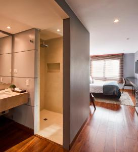 a room with a bedroom and a bed and a desk at Nico Apartasuites in Bogotá