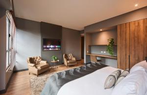 a bedroom with a large bed and two chairs at Nico Apartasuites in Bogotá