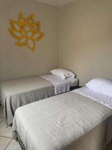 a room with two beds and a clock on the wall at Casa Maju Suítes in Búzios