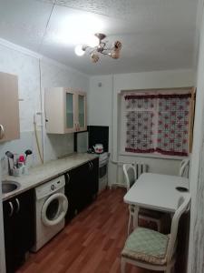 une cuisine avec une table et un évier, une table et une table dans l'établissement 7 дом у моря, à Aktau