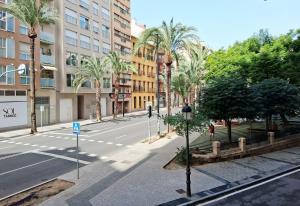 an empty street with palm trees and a building at AS ROOMS Alicante in Alicante